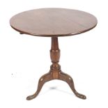 A George III Oak tilt top tripod table with baluster column and circular top, 72.