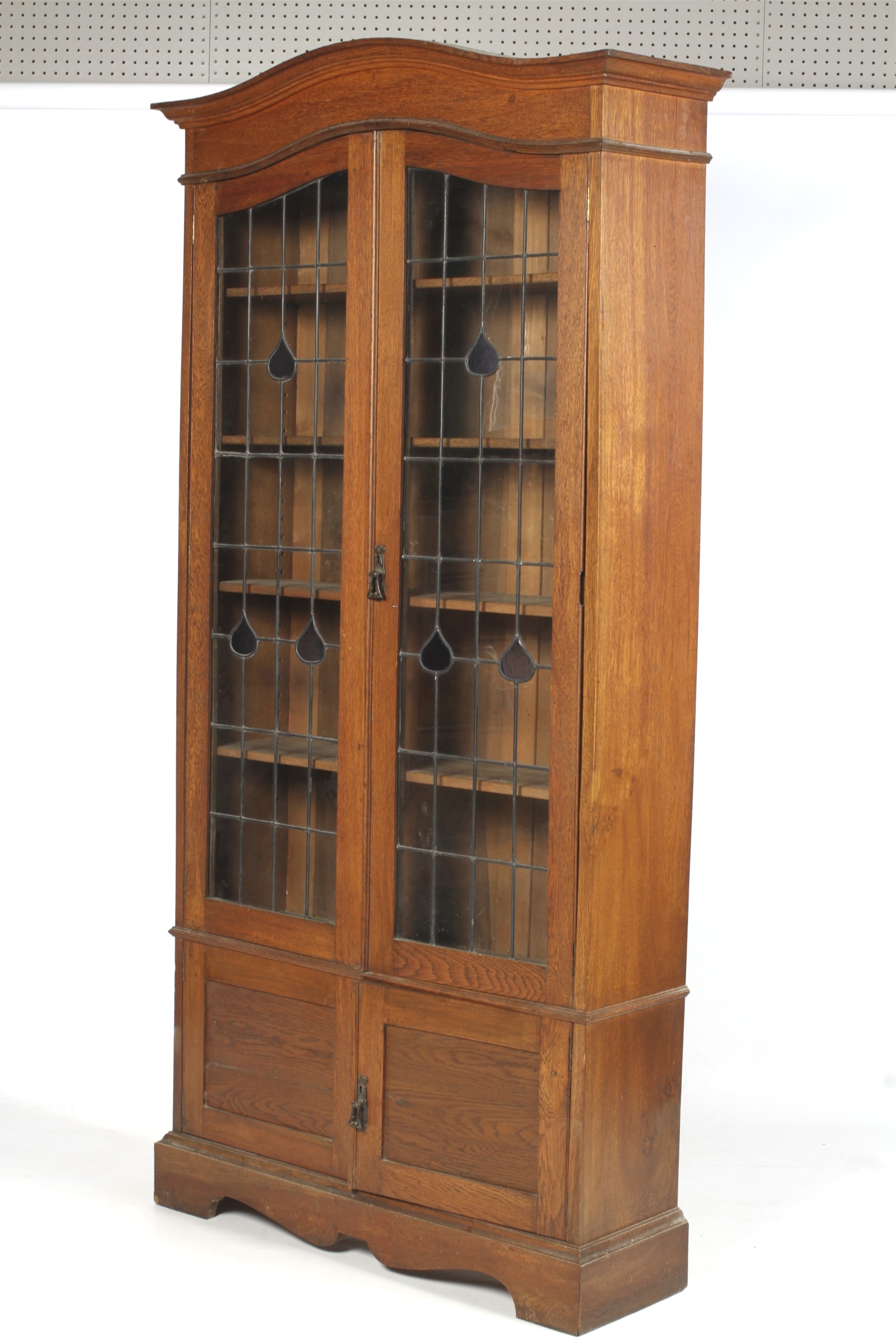 An Edwardian ( slight Arts and Crafts) bookcase with stained and leaded glass doors before an