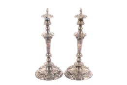 A pair of silver plated shaped-round candlesticks with flame finials,