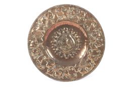A Newlyn School / Arts and Crafts copper embossed charger depicting a bird feeding young to centre