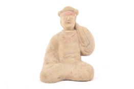 A Chinese terracotta figure of a kneeling man in Tang style with a raised arm in a voluminous