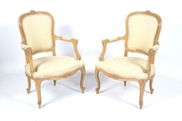 A pair of blonde beech fauteuils , open armchairs with sprung seats, upholstered arms,