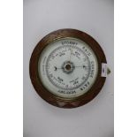 A vintage oak framed circular aneroid barometer.