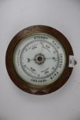 A vintage oak framed circular aneroid barometer.
