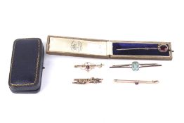 Four early 20th century gold and gem set bar brooches and an oval pyrope garnet stick pin.