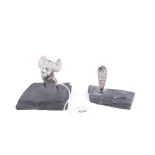 Two small silver sculptures on slate plinths.