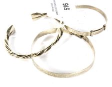 Three silver and white metal bangles. Including a torque example.