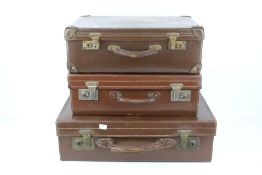 Three vintage brown suitcases. One leath