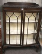 An Edwardian dark oak bow fronted display cabinet.