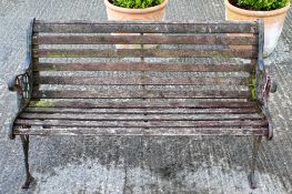 A traditional garden bench with cast iron ends and wooden slates.