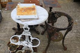Five cast metal table bases, an umbrella stand and a circular white marble table top.