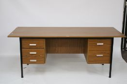 A 1970s teak veneer office desk. On square metal supports and drawers on either side.