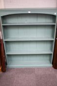 A free standing green painted bookcase. With three fixed shelves.