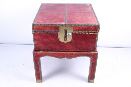 An Eastern red leather trunk on a stand.
