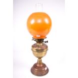 Mid-Century : A brass oil lamp with single burner and orange spherical shade.
