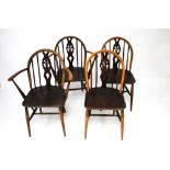 A set of four Ercol dining chairs. Arch top spindle back, two carvers and two others.