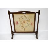 A mahogany framed fire screen with needlework centre.