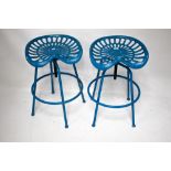 A pair of cast metal 'tractor seat' bar stools.
