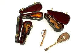 Three vintage miniature violins and two tortoiseshell mandolins.