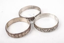 A silver broad slave bangle and two white metal examples.