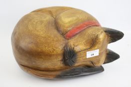 A life-size wooden carving of a sleeping cat.