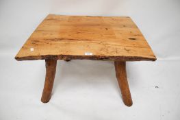 A rustic wooden coffee table. With bark sided planks on four tree trunk supports.