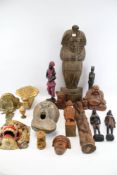 A collection of wooden carvings. Including tribal figures, a laughing buddha, masks, etc.