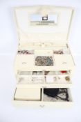 A cream coloured jewellery box carry case and contents.