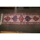A Persian handmade Kilim carpet runner decorated with figures in bright colours.