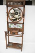 An Edwardian dark oak hallstand. With leaded glass panel and circular mirror, label 'J.