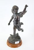 A cast figure of a standing cherub on a circular wood base.