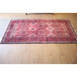 A Persian style red wool rug.