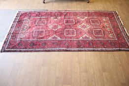 A Persian style red wool rug.