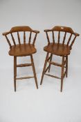 A pair of stained pine bar stools.