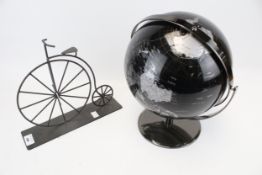 A vintage globe and a metal model of a penny farthing.