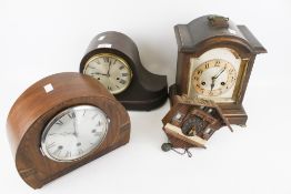 A group of three mantel clocks and a cuckoo clock.