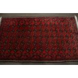 A Persian style red wool rug.