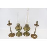 A pair of brass oil lamps and a pair of candlesticks.