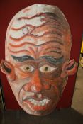 A large red painted face on hardboard.