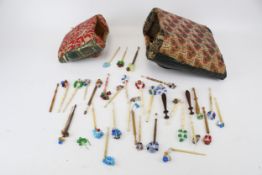 A collection of assorted lace-making bobbins with beads and two lace-making pillows