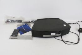 A Bose Wave music system CD player. S/N 033983382940048AC, with remote and instruction book.