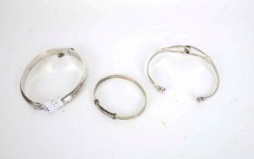 Three silver bangles including a torque bangle