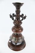 An early 20th century Japanese bronze candlestick with champleve enamel lotus decoration.