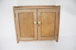 A small limed pine wall unit. With a single shelf behind double doors.