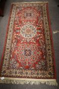 A Persian style wool rug with red ground and yellow border.