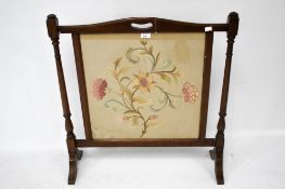 A mahogany framed fire screen with needlework centre.