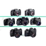 Seven black Praktica 35mm SLR cameras.