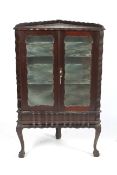 A dark wood early-mid 20th century mirror back colonial-style corner display cabinet.