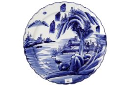 A Japanese blue and white charger. Painted with a landscape and with a fluted rim, diameter 41.
