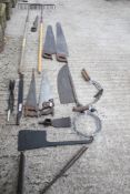 A collection of assorted vintage tools. Including carpenters' saws and garden rakes, etc.